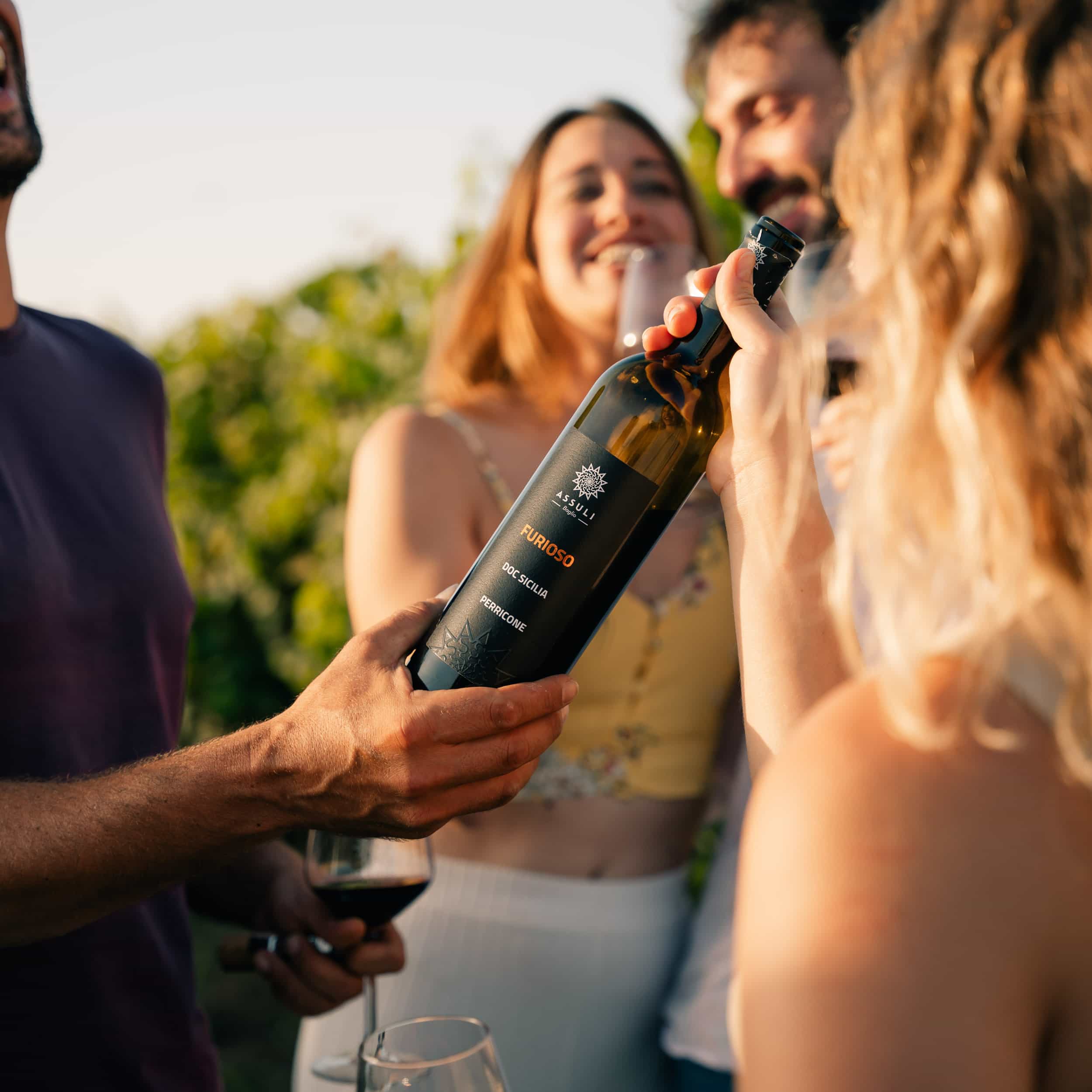 A guy passing red wine bottle to his girlfriend