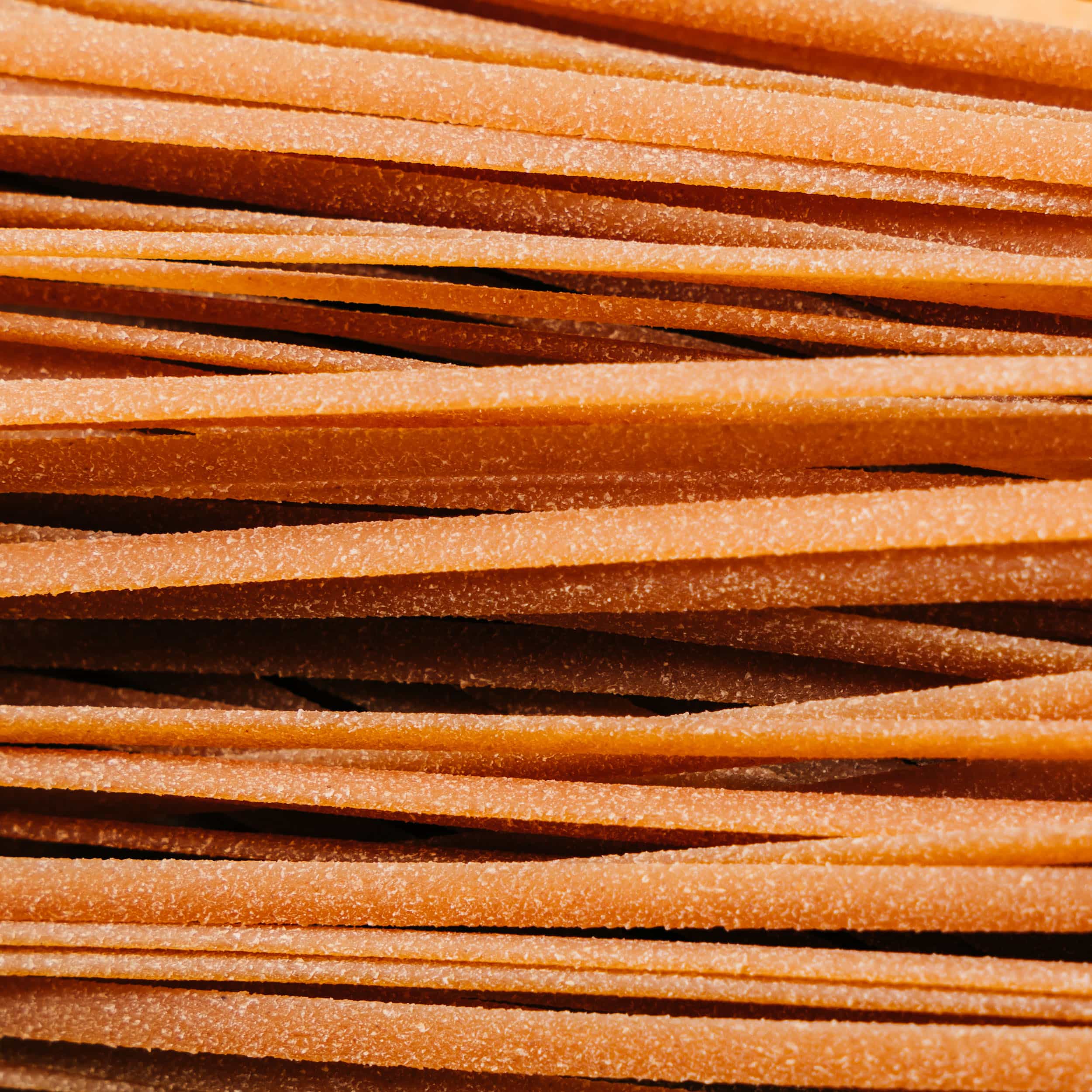 Close-up view of raw, textured pasta strips stacked together