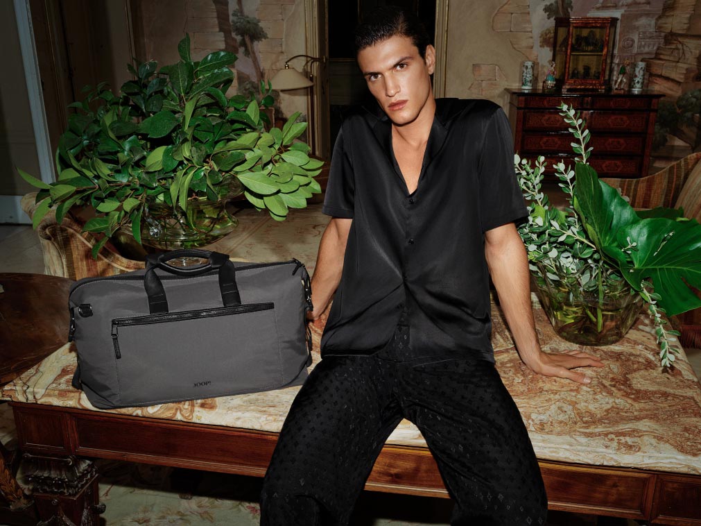 joop gentleman with black short sleeve shirt and black patterned trousers and black joop bag