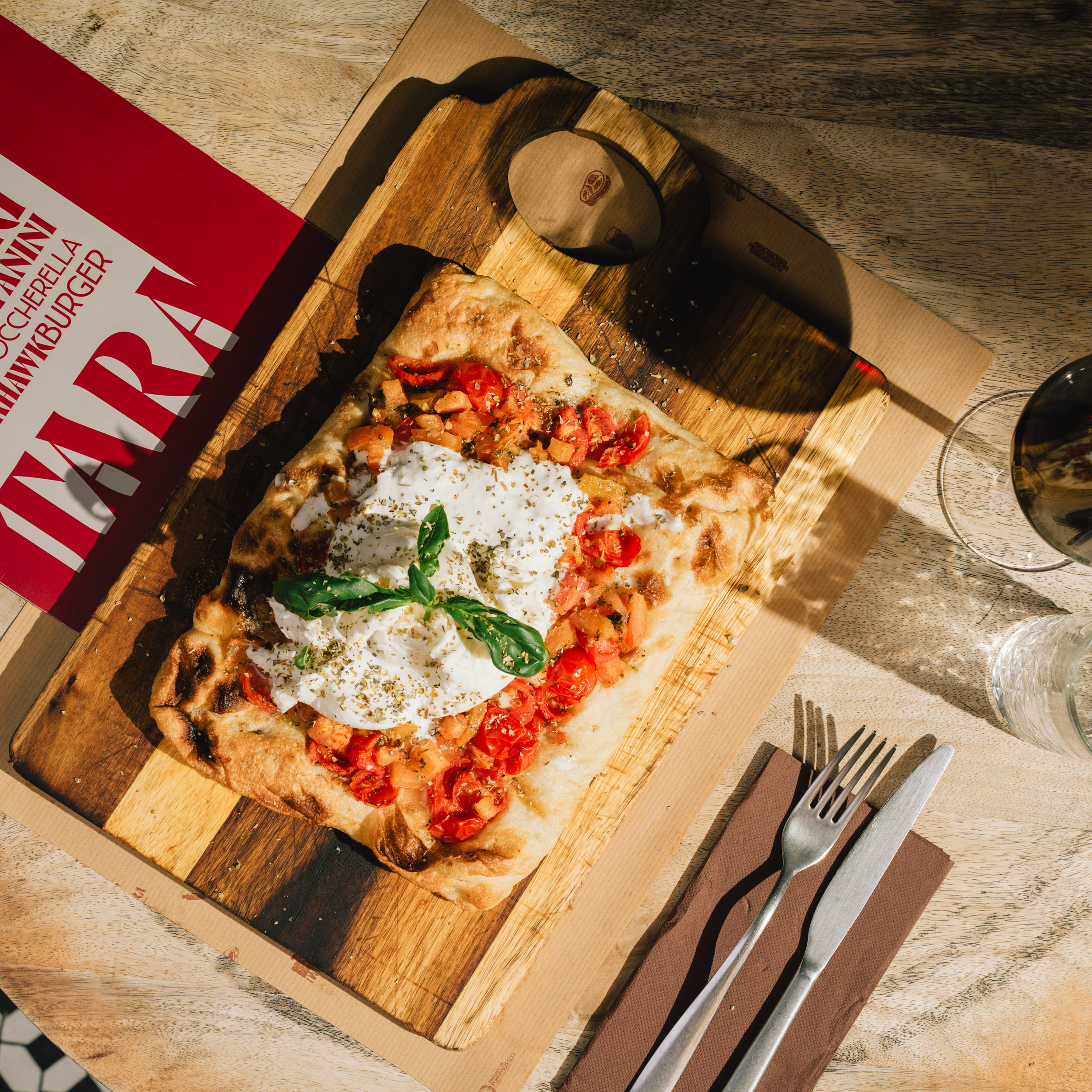 A top down photo of a pinza and a glass of wine