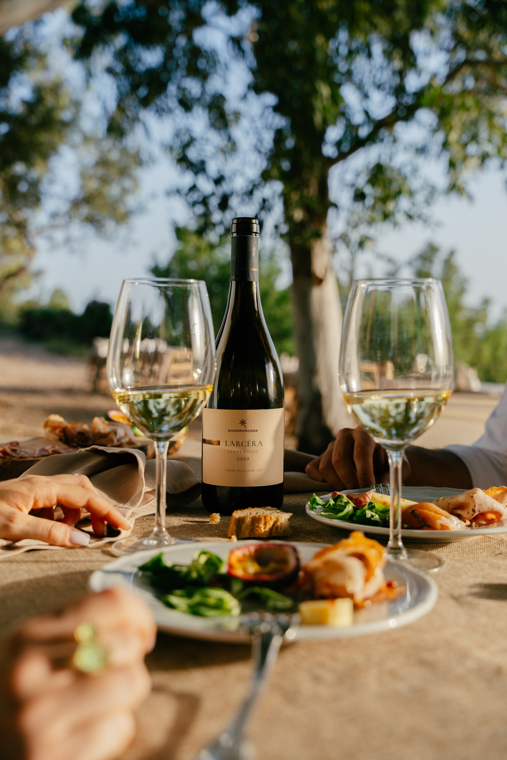 A bottle of white wine at the center of the table with some plates