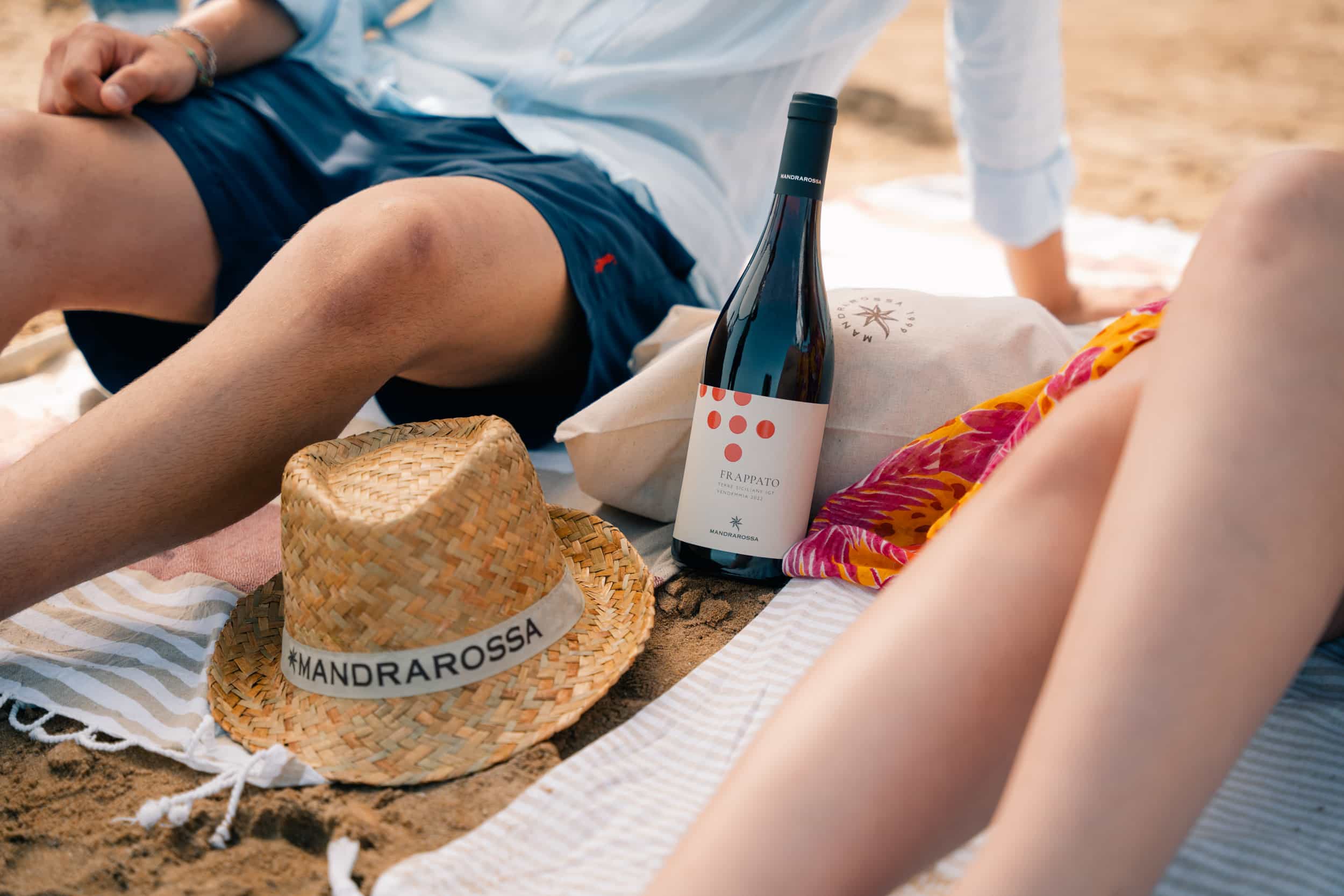 Two guys in the beach with a bottle of red wine