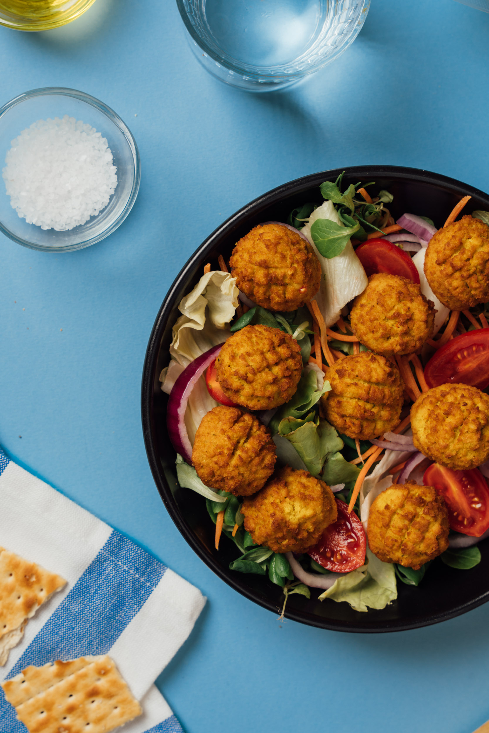 A close-up photo of a salad with falaffel in a blue background